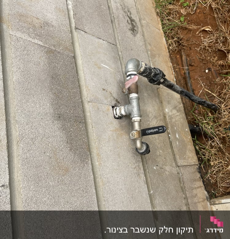 ברז מתכת עם צינור על רצפה מרוצפת